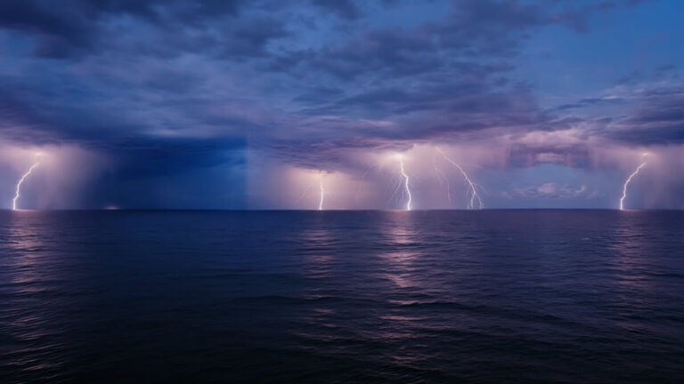 Nighttime ocean storm with several bright lightning bolts flashing across a dark, purple-tinged sky over the water.